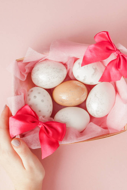 White Easter eggs in a nest on pink background. Design pastel tone in minimal flat lay - Foto, imagen