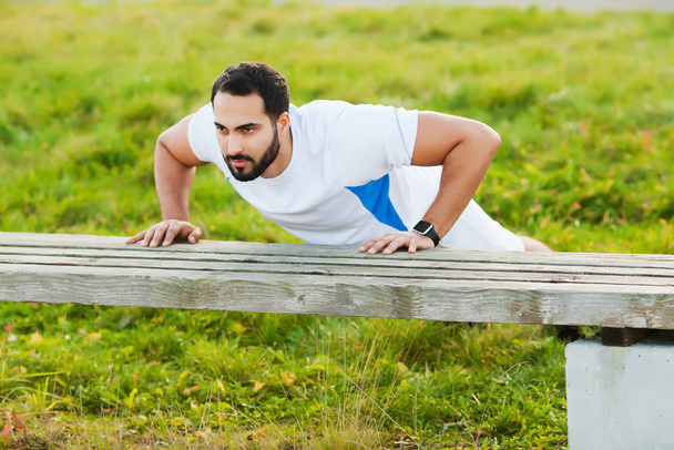 Fitness. Ejercicio push-up fitness hombre entrenamiento brazos músculos en el gimnasio al aire libre
 - Foto, Imagen