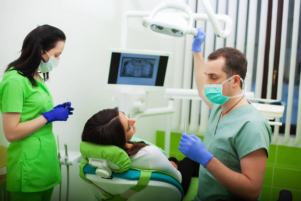 De tandarts man behandelen tanden naar client in tandheelkundige kantoor - Foto, afbeelding