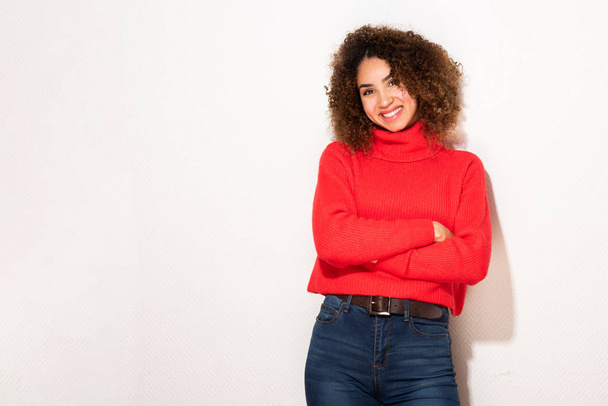 Ritratto di giovane donna afroamericana sorridente in maglione rosso con braccia incrociate da sfondo bianco
  - Foto, immagini