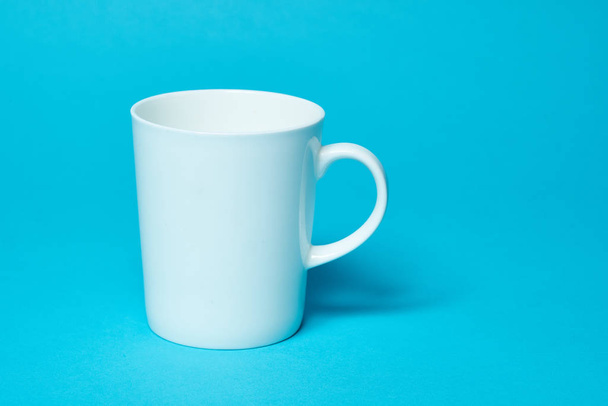 white cup isolated on a blue background. Free space for text. Simplicity. - Foto, Bild