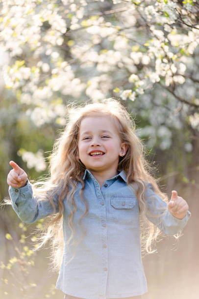 Little blonde girl having fun in the spring park. - Photo, Image