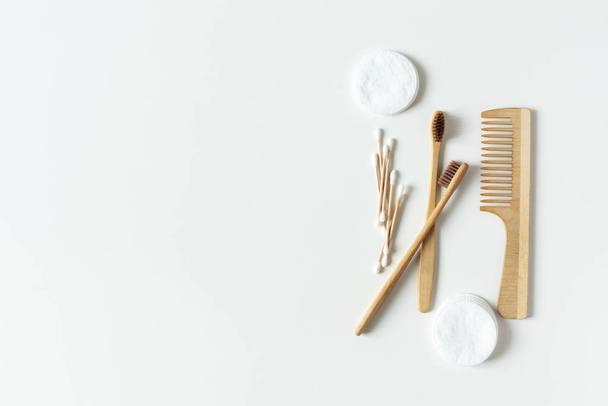 Dva biologicky rozložitelné, kompostovatelné bambusové zubní kartáčky, kartáček na vlasy a vatové podložky na bílém podkladu ležely. - Fotografie, Obrázek