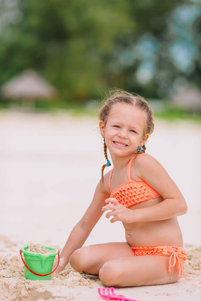 Очаровательная маленькая девочка играет с пляжными игрушками во время тропического отпуска
 - Фото, изображение