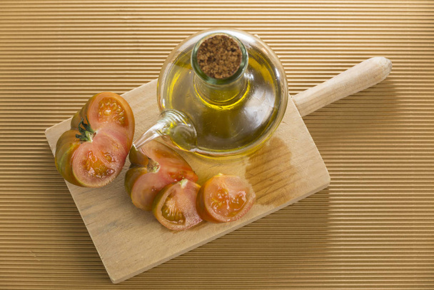 Ντομάτα κομμένη σε ξύλινη σανίδα, δίπλα σε ένα porron του πετρελαίου - Φωτογραφία, εικόνα