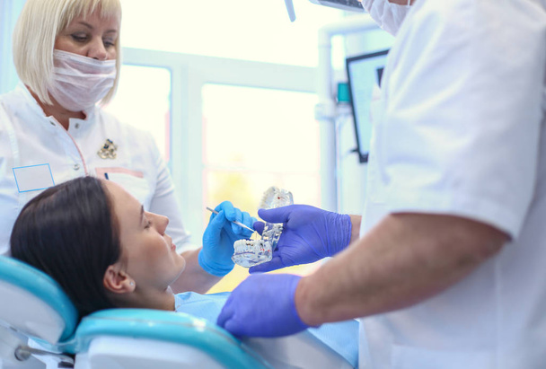 Portrait of a dentist who treats teeth of young woman patient - Fotografie, Obrázek
