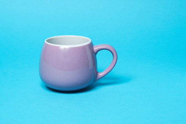 Lilac bright cup isolated on a blue background. Free space for text - Foto, Imagem