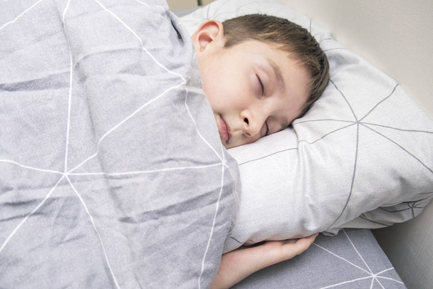 A preteen kid boy sleeping in bed at home, bedtime and sweet dreams concept - Foto, imagen