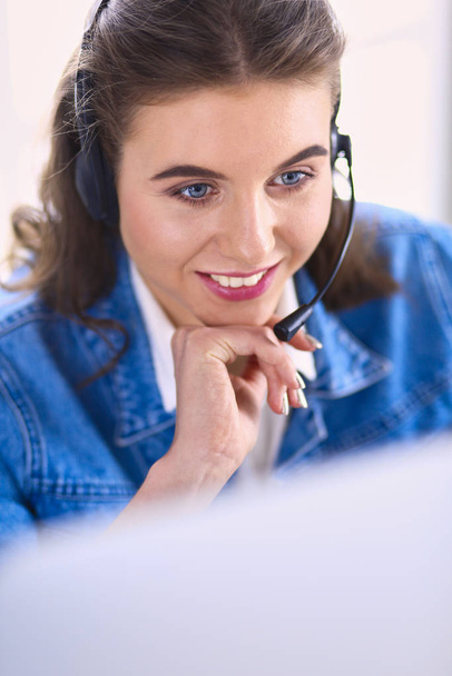 Portret pięknej bizneswoman pracującej przy biurku ze słuchawkami i laptopem - Zdjęcie, obraz