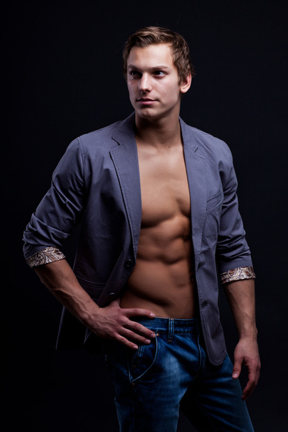 Young sexy macho man with open jacket over dark background - 写真・画像