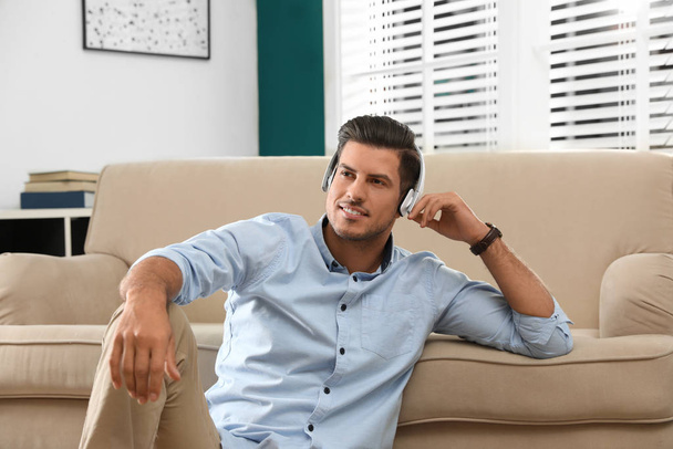 Man listening to audiobook near sofa at home - Foto, imagen