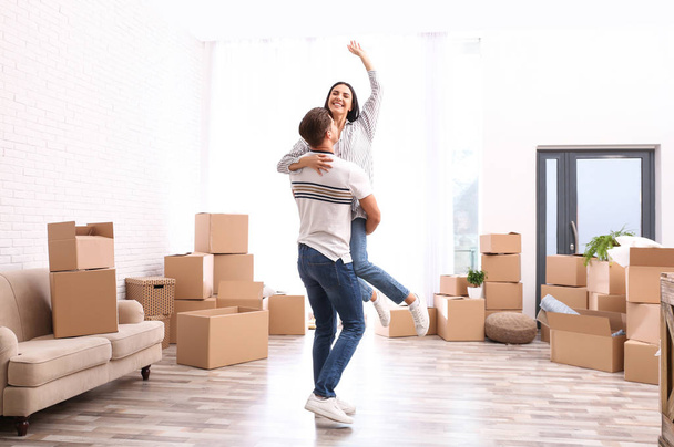 Happy couple having fun in room with cardboard boxes on moving d - Photo, image
