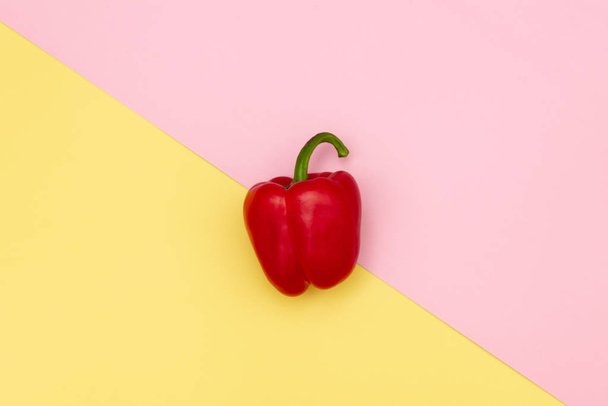 Red pepper on pink and yellow background - Фото, зображення