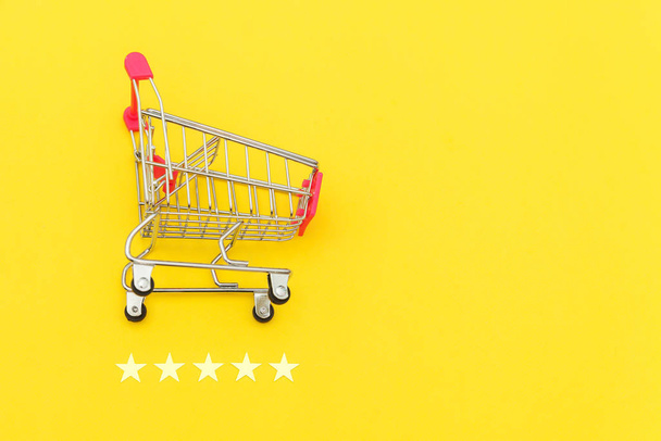 ホイールと5つ星評価黄色の背景に隔離されたショッピングおもちゃのための小さなスーパーマーケットの食料品プッシュカート。小売消費者オンライン評価とレビューの概念を購入. - 写真・画像