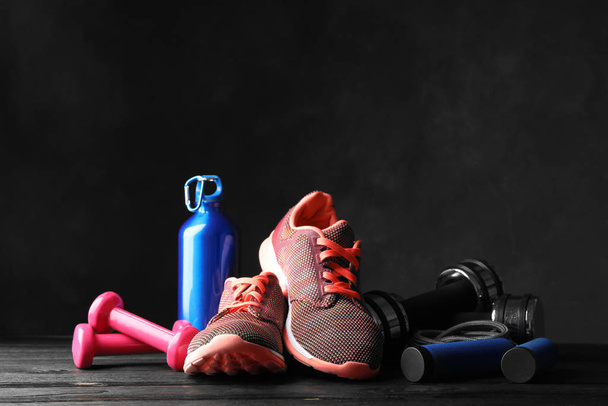 Gym equipment and accessories on wooden floor against dark background - Fotoğraf, Görsel