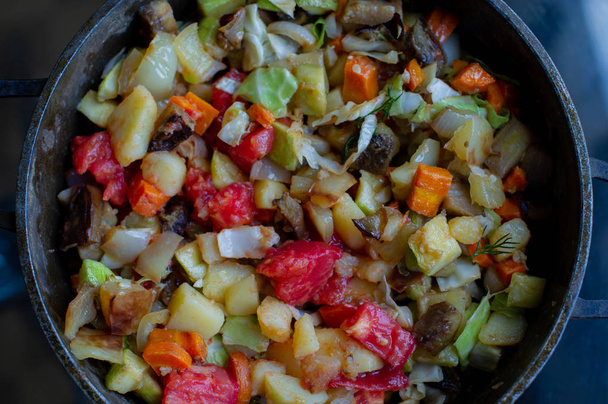 Des légumes. Pommes de terre, tomates, poivrons, aubergines, oignons, carottes, chou, courgettes frites en cubes dans une casserole
 - Photo, image