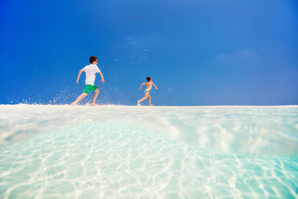 Kids having fun at tropical beach during summer vacation playing together at shallow water - 写真・画像