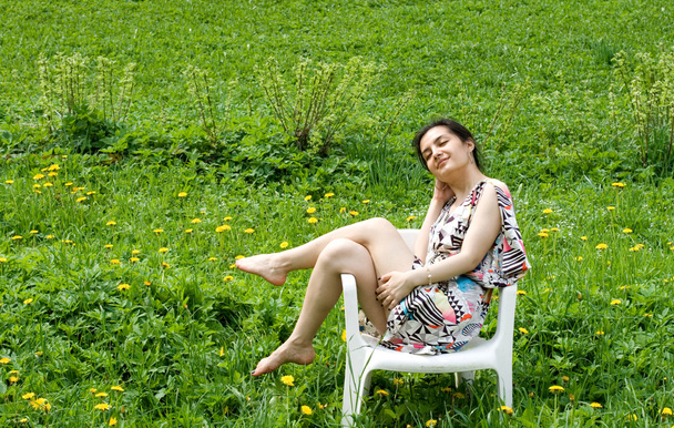 Girl resting in a chair among dandelions - Valokuva, kuva