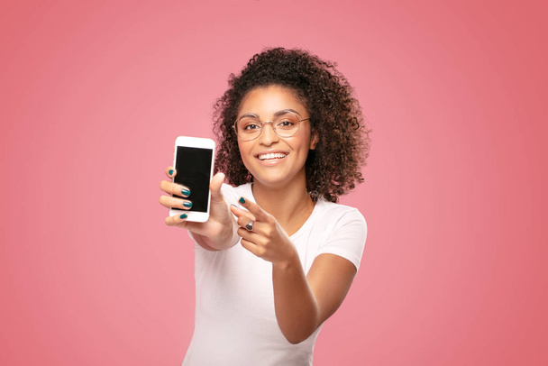 Smiling afro girl showing empty screen of mobile phone. - 写真・画像