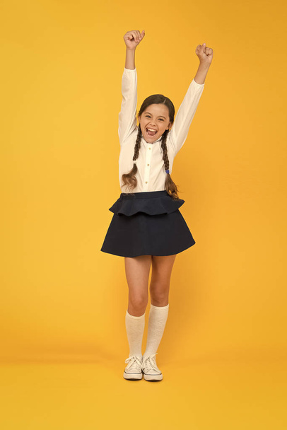 Celebrate knowledge day. September time to study. Girl adorable pupil on yellow background. School uniform and fashion. Back to school. Student little kid adores school. Emotional schoolgirl - 写真・画像