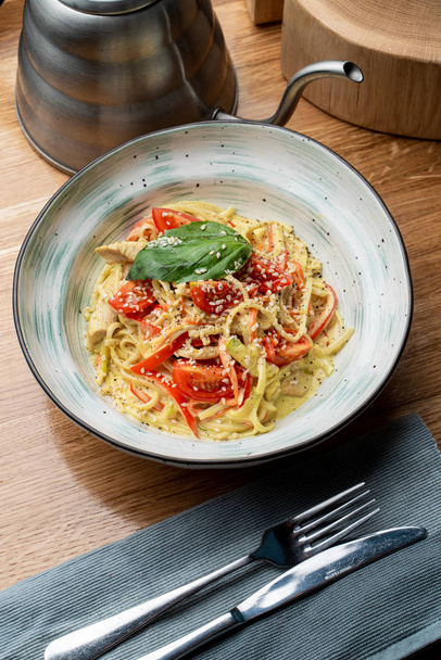 Pasta italiana con petto di pollo, salsa cremosa e formaggio sul tavolo di legno in un ristorante italiano
 - Foto, immagini