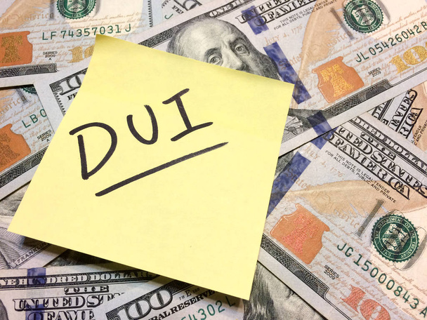 Αμερικανική μετρητά χρήματα και κίτρινο post it note with text DUI - Φωτογραφία, εικόνα