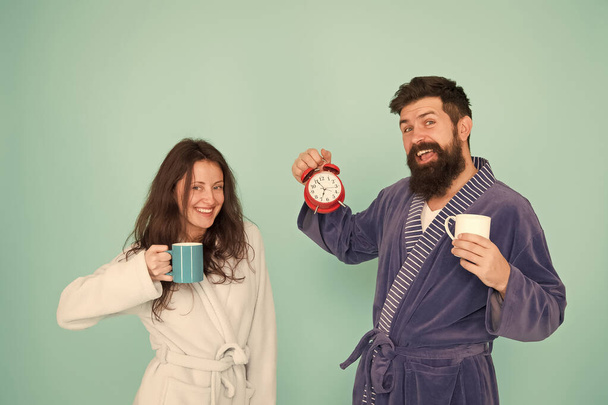 family life routine. couple in love alarm clock. love relations. tea time at home. hard morning. couple drink coffee. man beard and girl coffee cup. wakeup time. full of energy. energy and tiredness - Zdjęcie, obraz