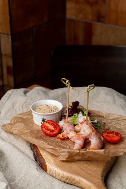King prawns coated in bacon with sauce and green salad - Photo, Image