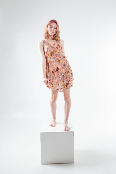 Young beautiful girl stands on barefoot cube and in a dress - 写真・画像