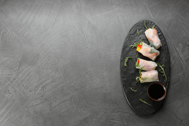 Delicious rolls wrapped in rice paper served on grey table, top view. Space for text - Foto, imagen