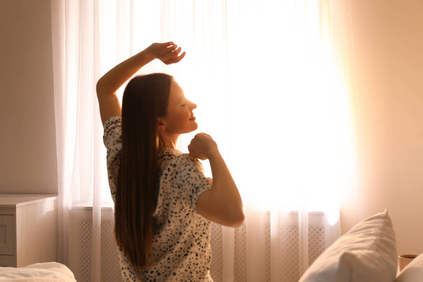 Молодая женщина растягивается на кровати дома. Ленивое утро
 - Фото, изображение
