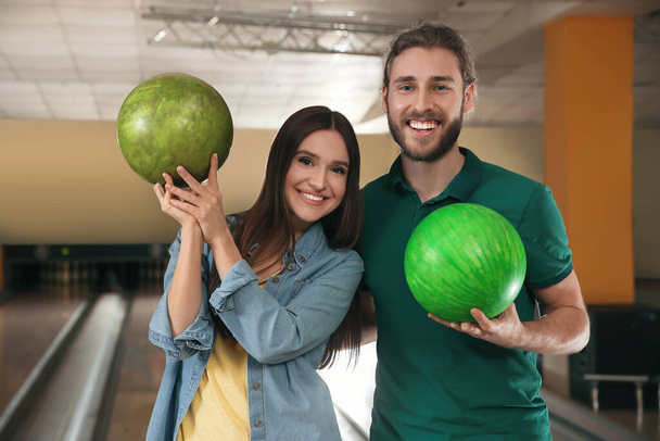 Happy young couple with balls in bowling club - Fotoğraf, Görsel