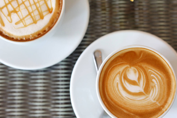 Kahve masasında sıcak karamelli macchiato ve sütlü kahve. - Fotoğraf, Görsel