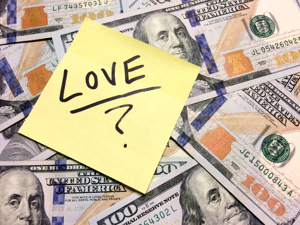 Американские наличные деньги и желтый пост это записка с текстом Любовь с вопросительным знаком
 - Фото, изображение