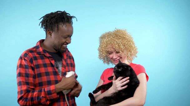  African male and a Caucasian woman . holding a black cat and a white rat.  - Photo, image
