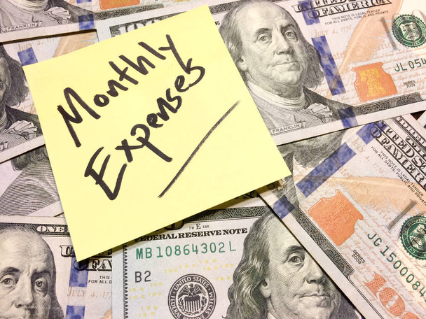 Αμερικανική μετρητά χρήματα και κίτρινο post it σημείωμα με κείμενο Μηνιαία έξοδα - Φωτογραφία, εικόνα