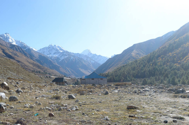 Een berghut hut in de hoge Himalaya bergen, gelegen om onderdak te bieden aan bergbeklimmers, klimmers en wandelaars. Een elkaar overlappende heuvelrug V-vormige vallei op de achtergrond. - Foto, afbeelding