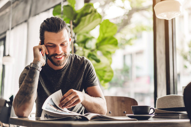 Yakışıklı sakallı hipster adam masada kahve ile akıllı telefon kullanımı - Fotoğraf, Görsel