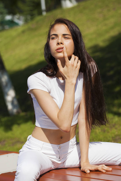 Beautiful brunette woman posing against summer park, bright sunn - 写真・画像