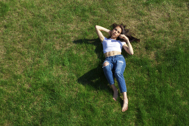 Portrait of a young beautiful girl resting on the lawn in the pa - Фото, зображення