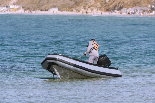 Een man bestuurt de boot die in zee vaart. - Foto, afbeelding