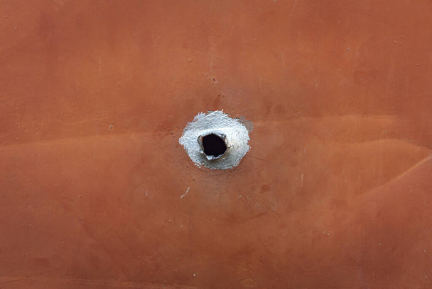 agujero de bala externo. agujero con centro negro en la placa de hierro
 - Foto, imagen