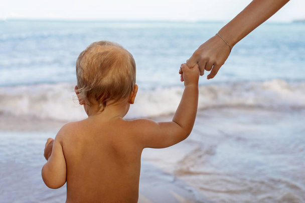 Little kid holding hands with faceless mom in beach - Photo, Image