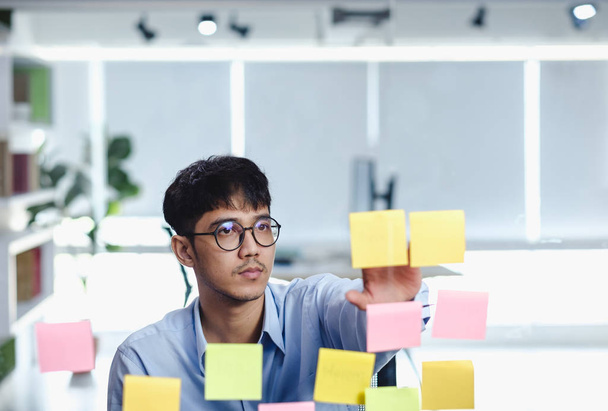 asian businessman looking and writing on sticky note for brainst - Foto, Imagem