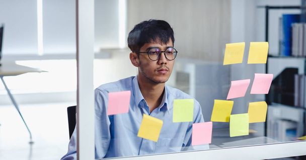asian businessman looking and writing on sticky note for brainst - Foto, Imagem