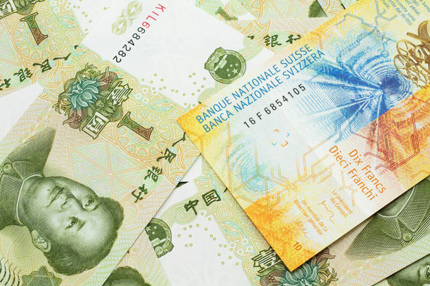 A yellow, ten Swiss franc note from Switzerland close up in macro with Chinese one yuan bills - Photo, Image
