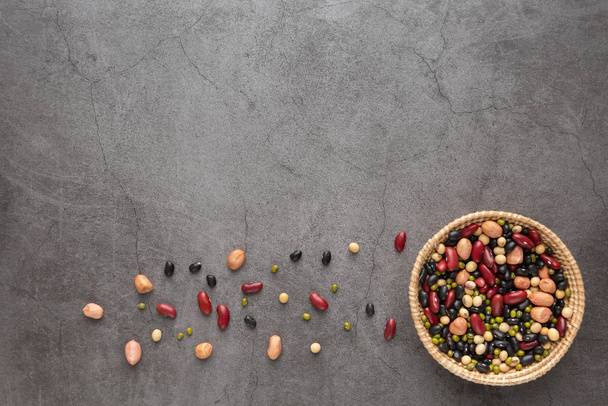 Grains or beans, red bean, black bean, green bean, soybean, peanut in the wooden basket placed on the black cement floor. Top view. - Φωτογραφία, εικόνα