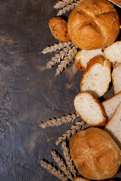 ассортимент разнообразного свежего хлеба на темном фоне, вертикальный
 - Фото, изображение