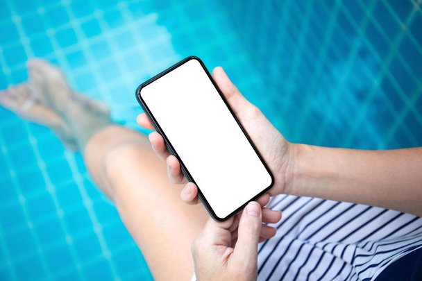 γυναικεία χέρια κρατώντας τηλέφωνο με απομονωμένη οθόνη στην πισίνα - Φωτογραφία, εικόνα