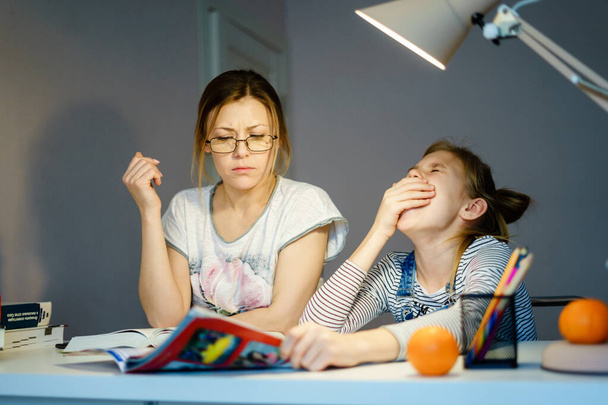 Mère aidant sa fille fatiguée avec des devoirs à la maison
. - Photo, image
